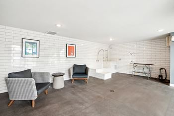 a living room with chairs and a bathroom with a tub and a sink